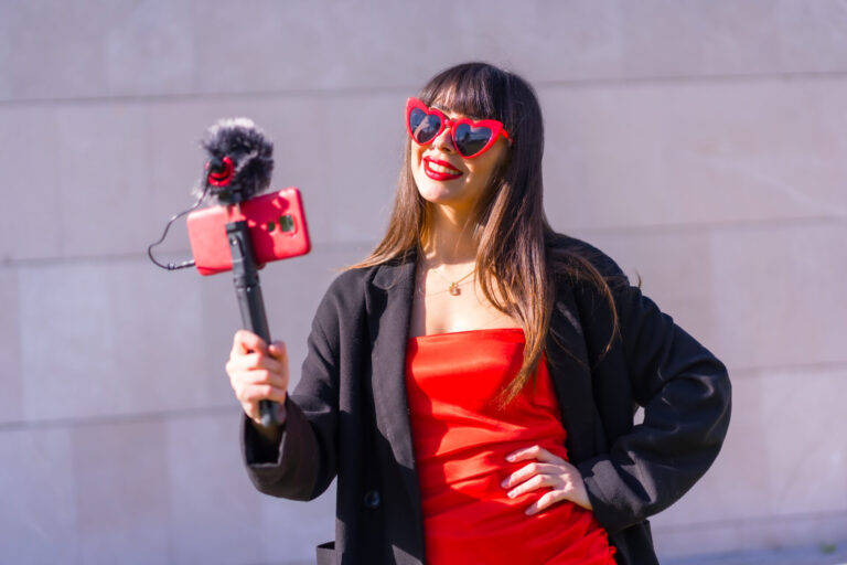 brunette caucasian girl making vlog valentines day social networks sunglasses with red hearts phone microphone gray background