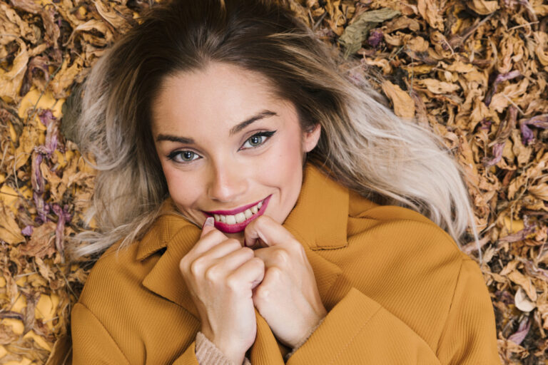 Horoskop na listopad 2026: Raci si řeknou o změnu, Váhy narazí na zajímavou nabídku smiling modern woman lying dry leaves holding yellow jacket looking camera